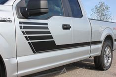 a white truck with black stripes parked in a parking lot