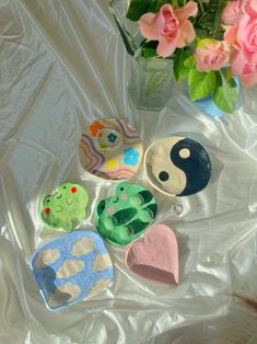 several decorated cookies sitting on top of a white sheet next to a vase filled with flowers