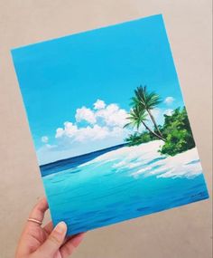 a hand holding up a painting of a beach with palm trees