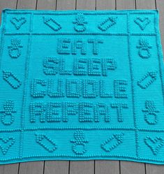 a crocheted blue rug with words and symbols on the front, sitting on a wooden floor