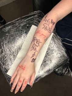 a woman's foot with flowers on it and writing on the side of her arm