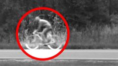 a blurry image of a bicyclist riding on the road with trees in the background