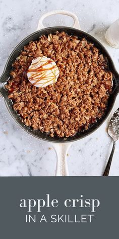 an apple crisp in a skillet with vanilla ice cream on top and spoons next to it