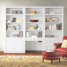 a living room with white bookcases and a red chair in front of it