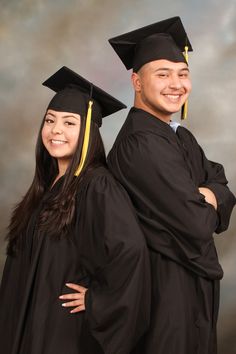 two people in graduation gowns posing for a photo with their arms around each other