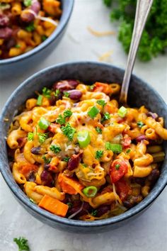 two bowls filled with pasta and veggies on top of a white countertop