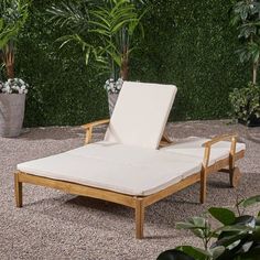 an outdoor chaise lounge chair in front of a green wall and potted plants