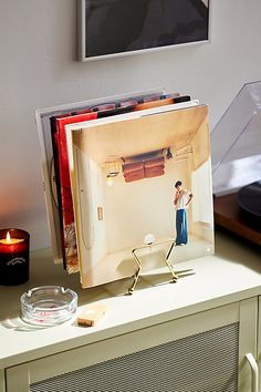 a record player sitting on top of a white table next to a glass bowl and candle