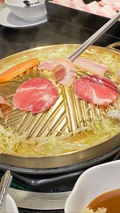 the food is being cooked on the stove in the kitchen with chopsticks and tongs