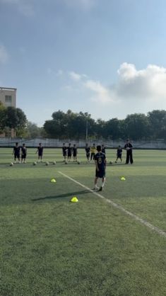 a group of people on a field with yellow balls in the air and one person standing at the end of the field