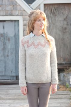 a woman standing in front of a building wearing a sweater with an arrow design on it