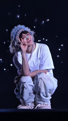 a woman sitting on top of a stage with her hands to her face while wearing a furry hat