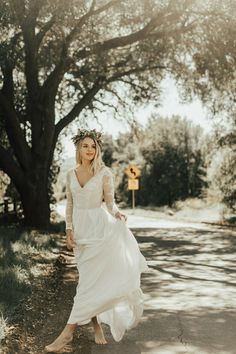 a woman is walking down the road wearing a white dress and a crown on her head