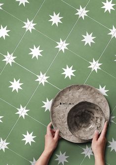 a person holding a hat on top of a green and white tile floor with stars