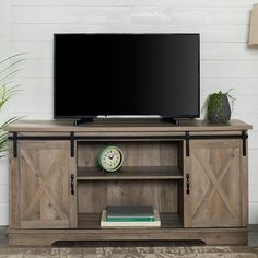 a flat screen tv sitting on top of a wooden entertainment center next to a potted plant