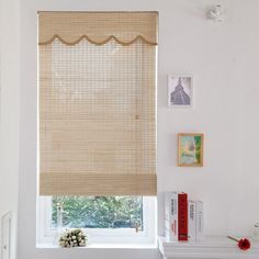 a room with a window covered in blinds and pictures on the wall behind it,