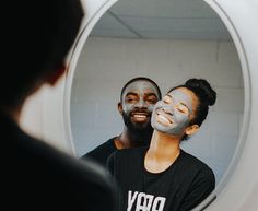 a man and woman are looking at their faces in the mirror while they both have facial masks on