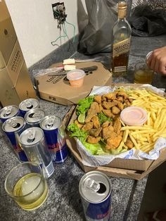 a table topped with lots of food next to cans of sodas and bottles of beer