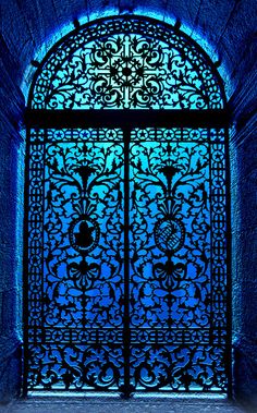 an ornate iron door with blue light coming through it