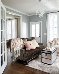 a living room filled with furniture and a chandelier hanging from the ceiling above