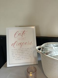 a table topped with a white basket filled with cloths next to a sign that says cafe night diapers