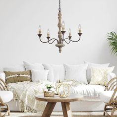 a living room filled with furniture and a chandelier hanging from the ceiling next to a white couch