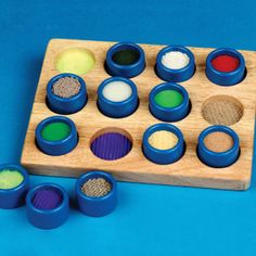 a wooden tray filled with different colored powders on top of a blue tablecloth