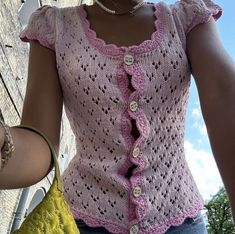 a close up of a person wearing a pink shirt and holding a yellow handbag