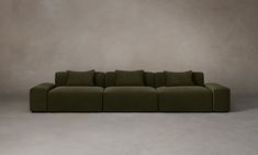 a large green couch sitting on top of a white floor next to a gray wall