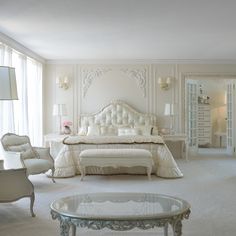 a bedroom with white furniture and flowers in vases