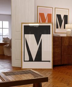 three framed art pieces on the wall in a room with wood floors and wooden furniture