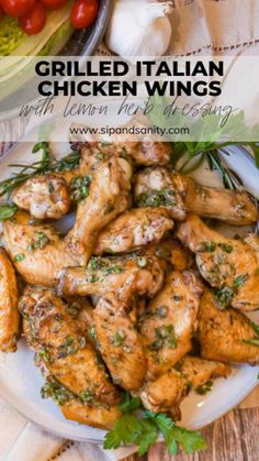 grilled italian chicken wings with lemon herb dressing on a white plate next to tomatoes and lettuce