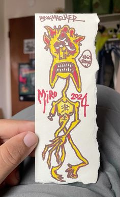 a person holding up a piece of paper with an image of a demon on it