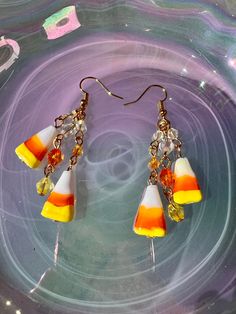 three candy corn earrings on a purple plate