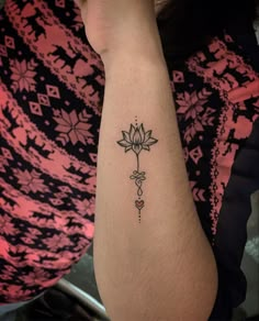 a woman's arm with a small flower tattoo on the left side of her arm