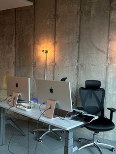 two computers sitting on top of a desk next to each other in front of a wall