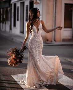 a woman in a wedding dress is crossing the street with her hand on her hip