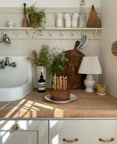 a kitchen counter with candles on top of it and some plants in the corner near the sink