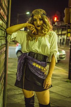 a woman is standing on the sidewalk in her short skirt and headband, with one hand on her hip