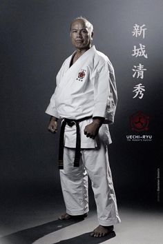 an older man standing in front of a wall with chinese writing on it and wearing a black belt