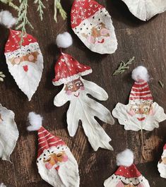 several gnomes made out of paper on a wooden table with pine branches and white pom - poms