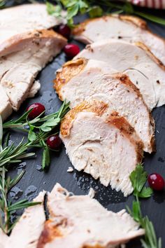 sliced turkey with cranberries and herbs on a black platter, ready to be served