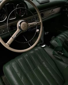 the interior of a classic car with green leather seats and steering wheel, along with dashboard controls