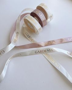 three rolls of satin ribbons with the words gardenia printed on one side and two spools of ribbon on the other