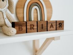 a wooden block spelling the word briar next to a teddy bear on a shelf