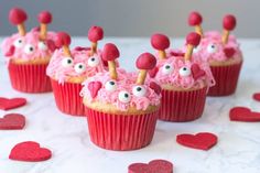 cupcakes decorated with pink frosting and googly eyes are on a table