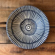 a black and white plate sitting on top of a wooden table next to a wall