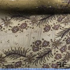 an embroidered fabric with gold and brown flowers on it, in the middle of a ruler