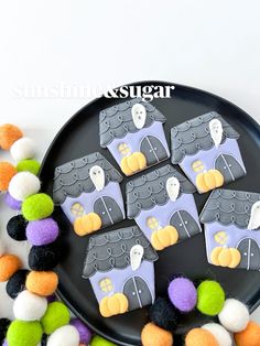 a black plate topped with lots of halloween treats next to pom - poms