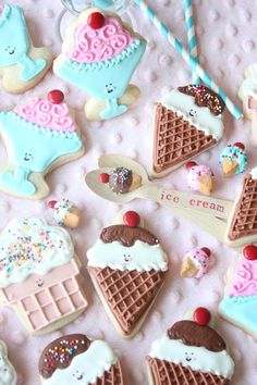 decorated ice cream and dessert cookies on a pink tablecloth with strawberries, blue striped lollipop sticks